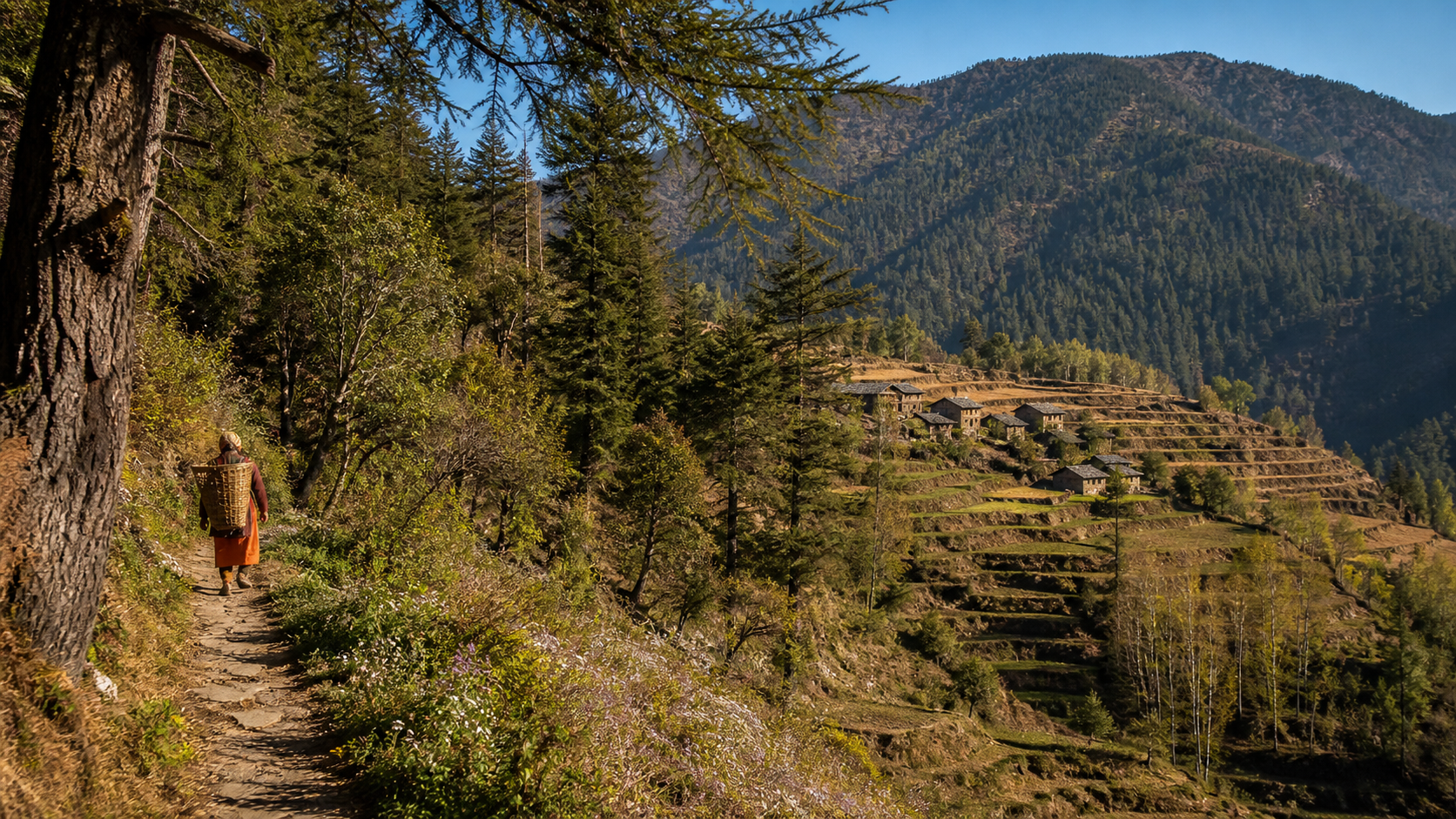A forest path overlooking a terraced mountain village in rural India